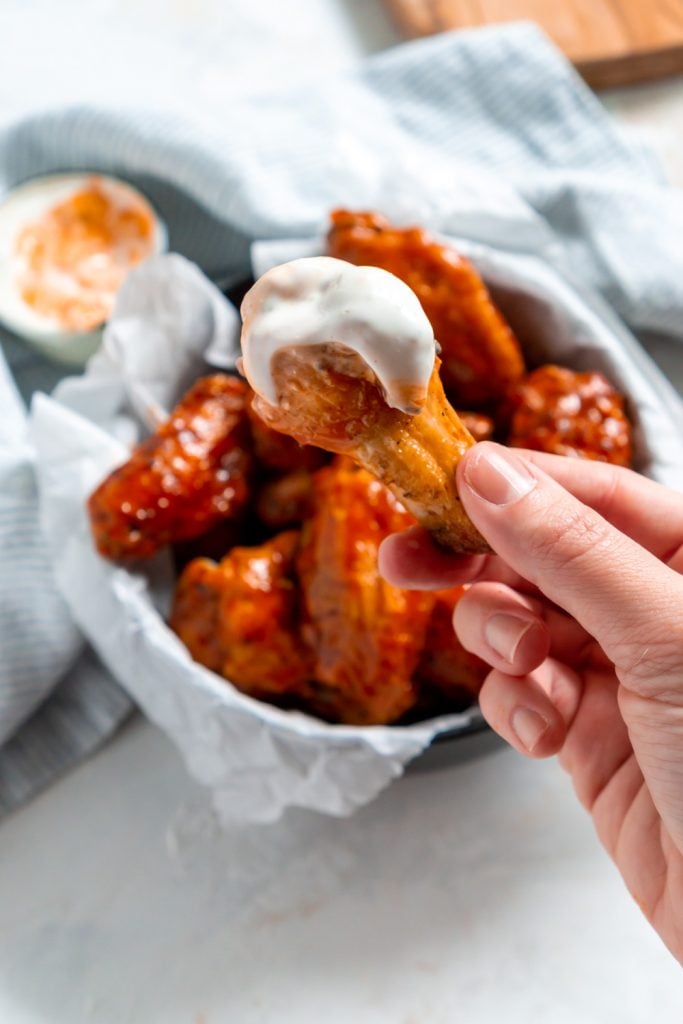 hand holding a buffalo wing dipped in blue cheese dressing
