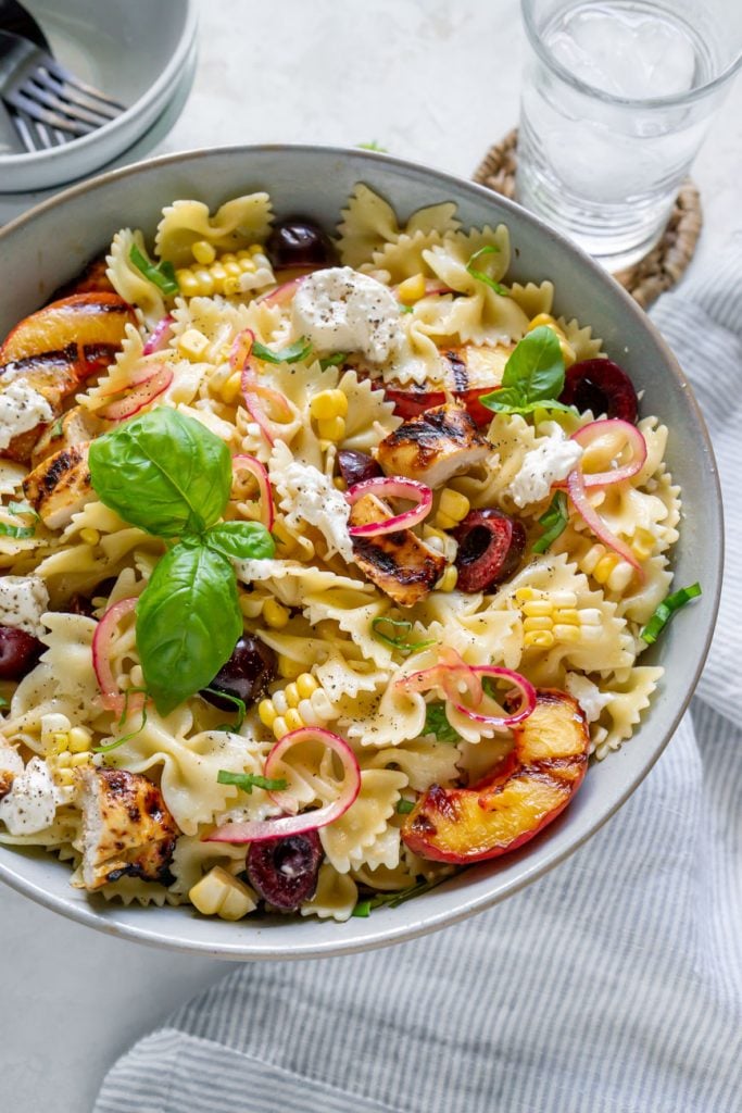grilled chicken pasta salad in a large bowl with a basil garnish