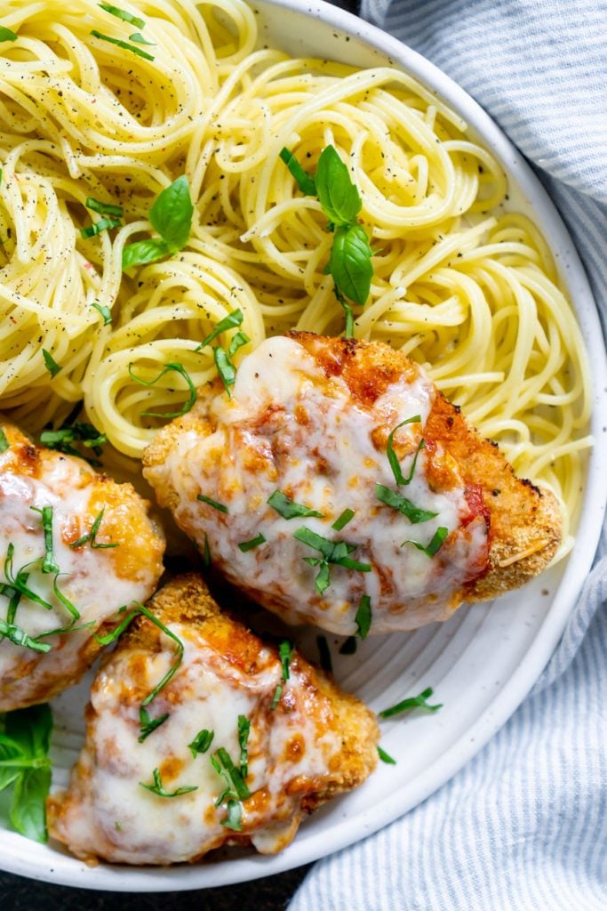 air fryer chicken parmesan on a white plate with spaghetti