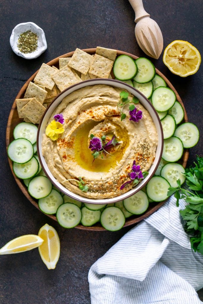 humus in a bowl with cucumber and chips