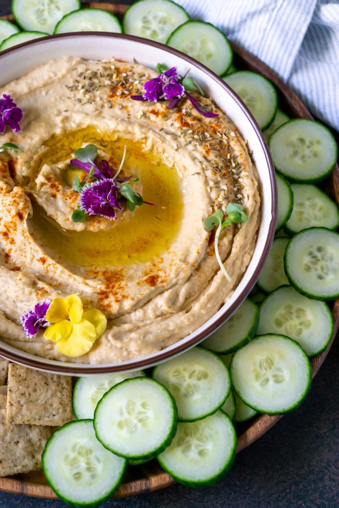 close up of hummus in a bowl with flowers