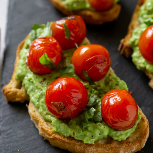 pea pesto tomato crostini on a black slate