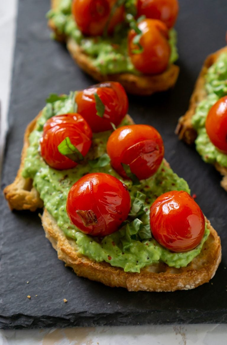 pea pesto tomato crostini on a black slate