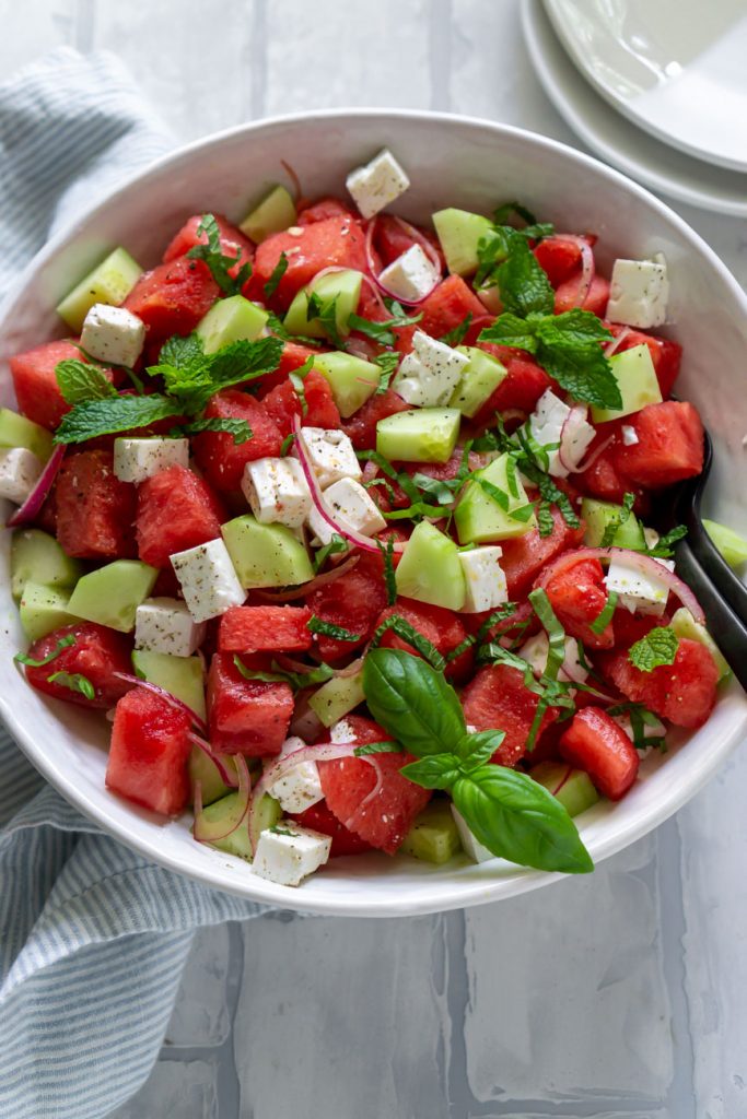 watermelon feta salad in a white bowl with black forks
