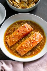 two salmon fillets marinating in a white bowl
