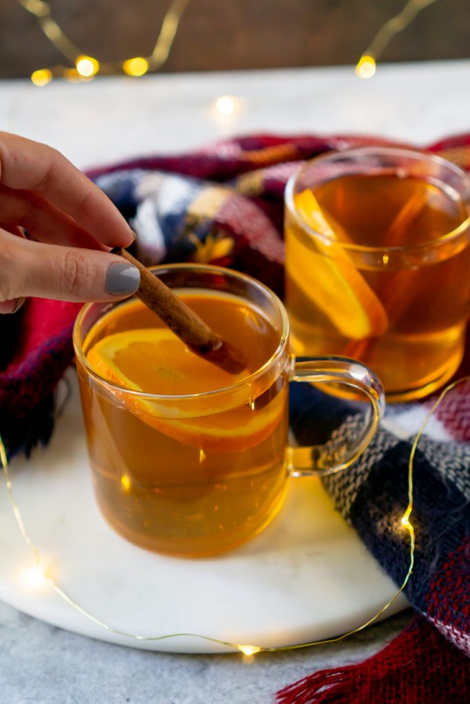 garnishing a hot toddy with a cinnamon stick