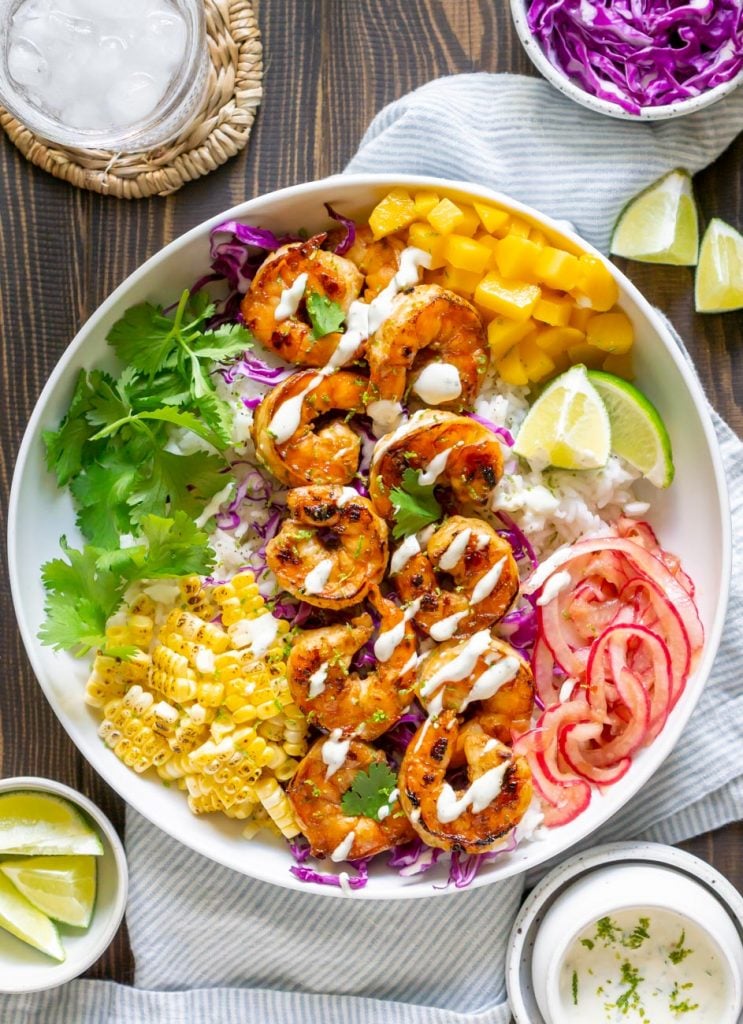 shrimp taco bowl with water, limes, and crema