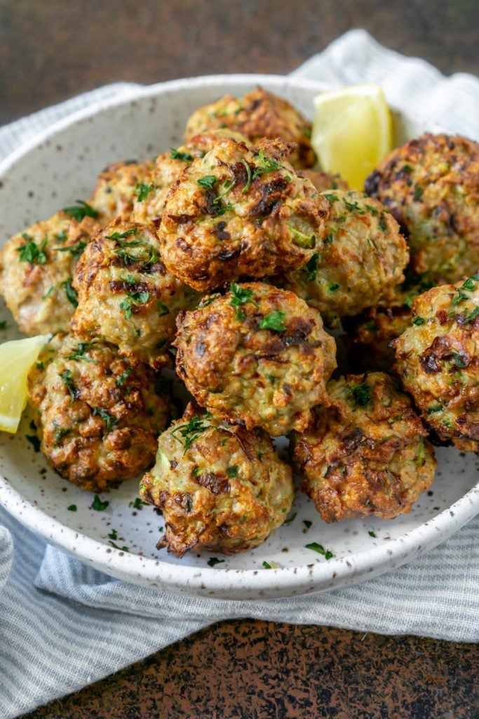 air fryer meatballs on a white plate with a lemon wedge