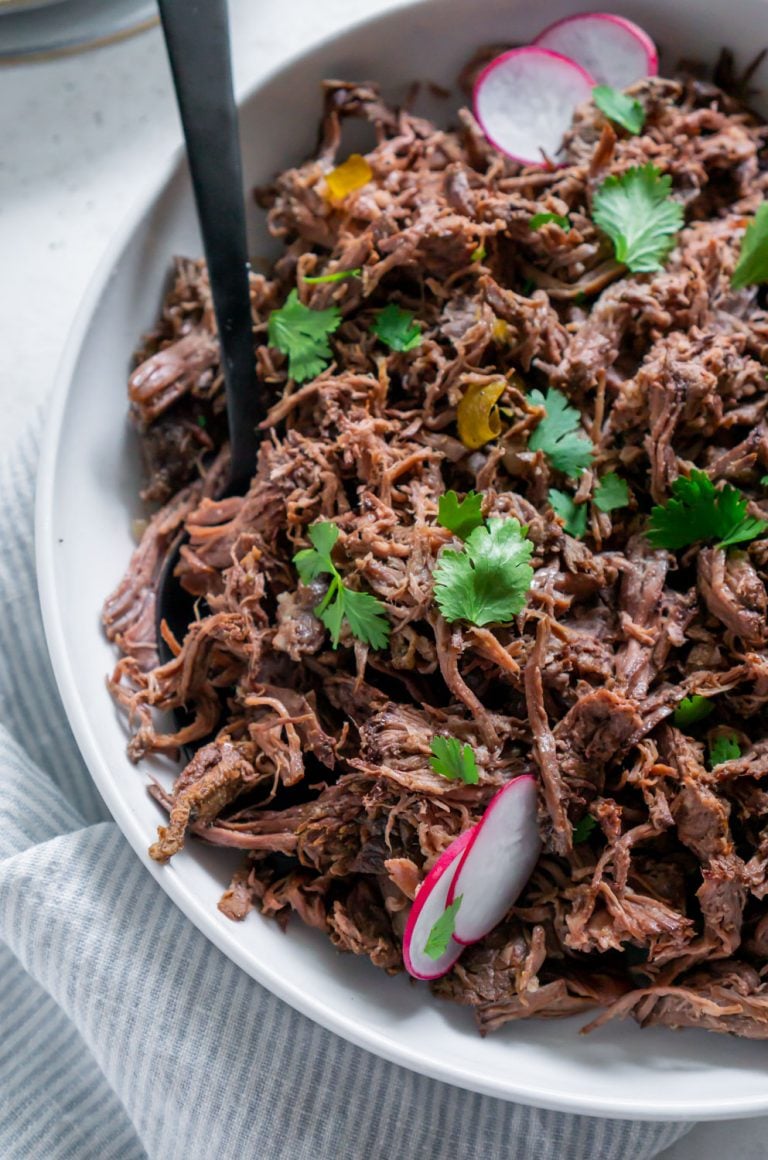 chipotle barbacoa in a white bowl with a black spoon