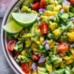 mango salsa in a bowl with lime wedges