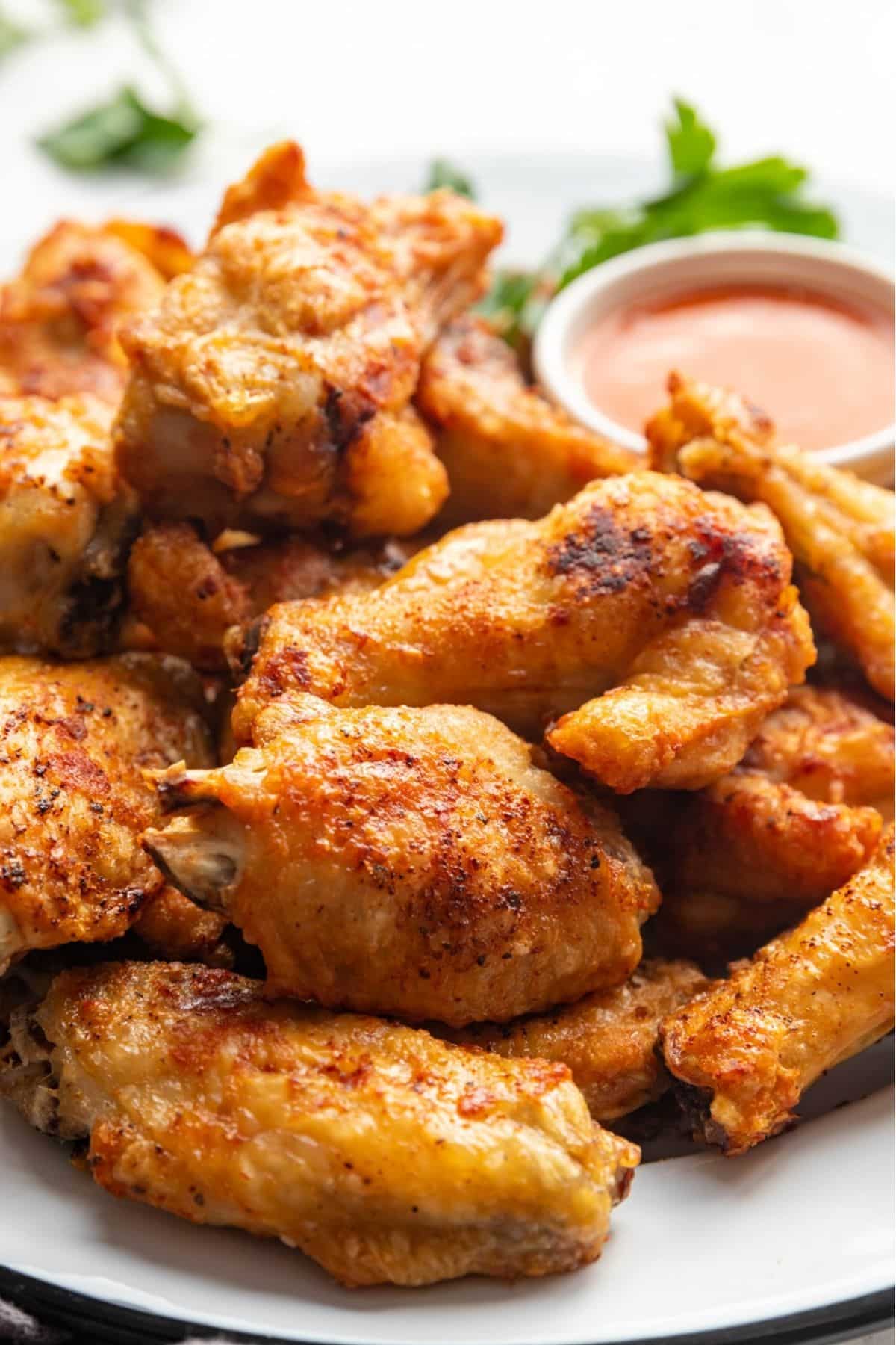 Air Fryer Chicken Wings on a white plate with wing sauce.