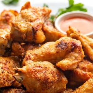 Air Fryer chicken wings on a white plate with wing sauce.