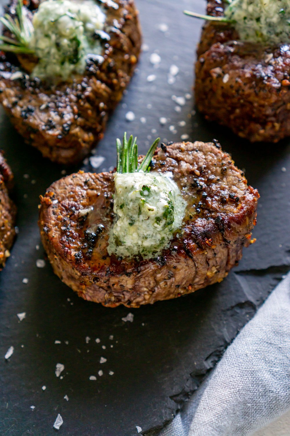 Steaks on a black serving board.