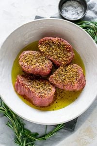 steaks marinating in a white bowl