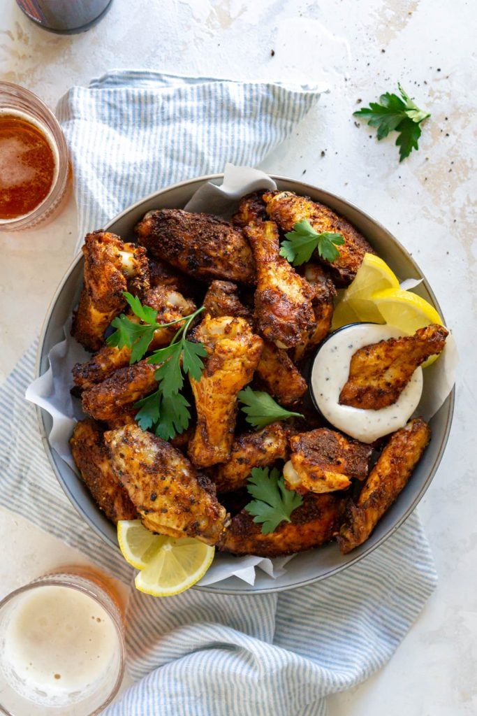 lemon pepper wings in a large bowl with two glasses of beer