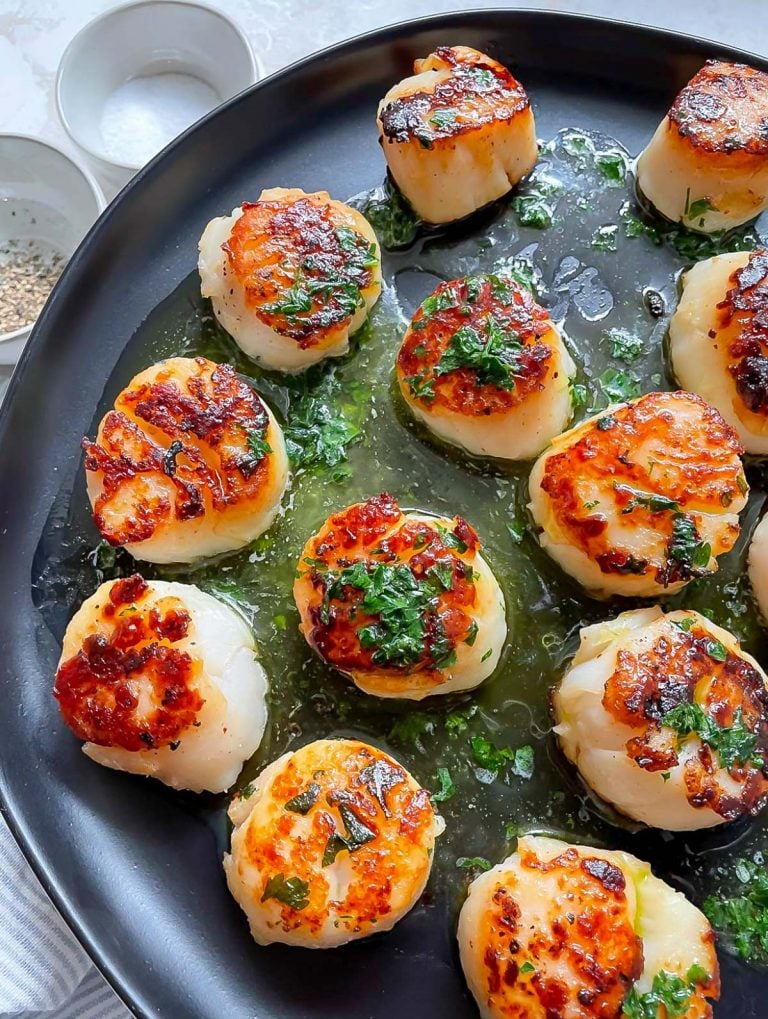 seared scallops on a black plate