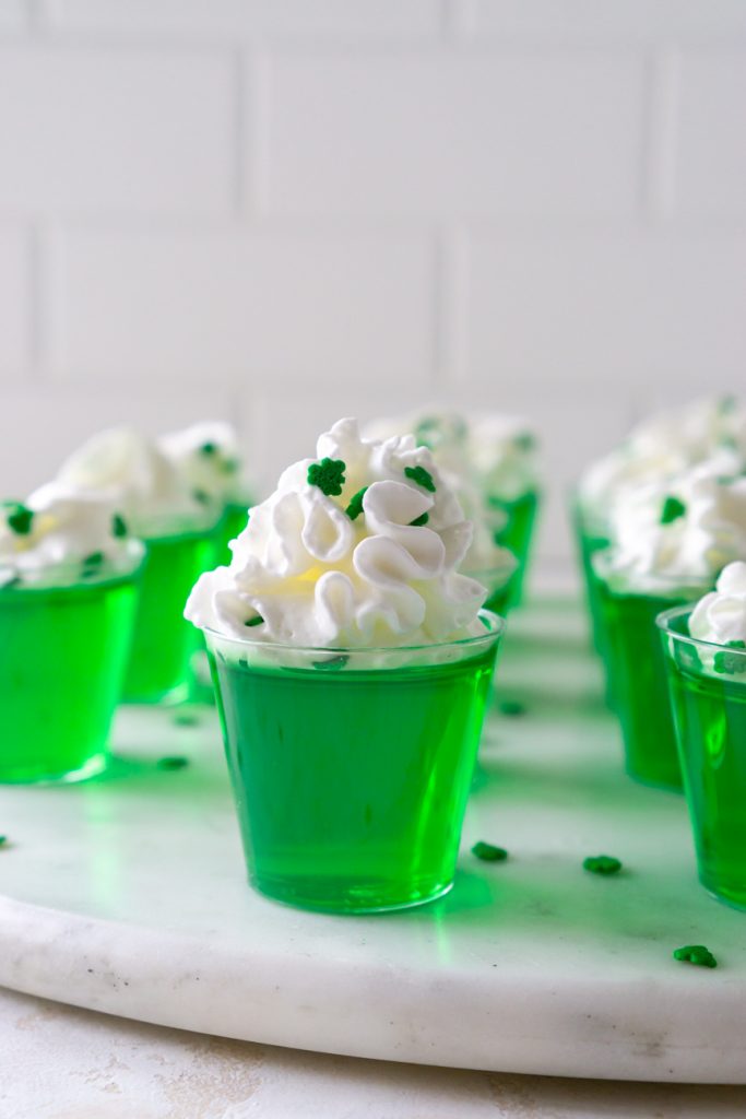 green vodka jello shots on a marble serving tray