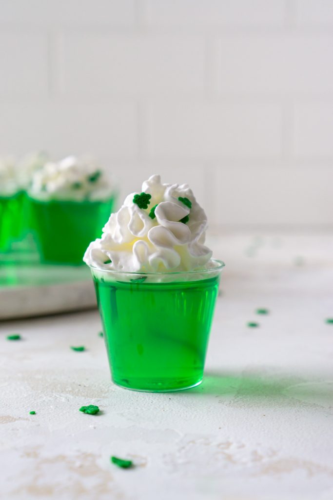 a green vodka jello shot with clover sprinkles
