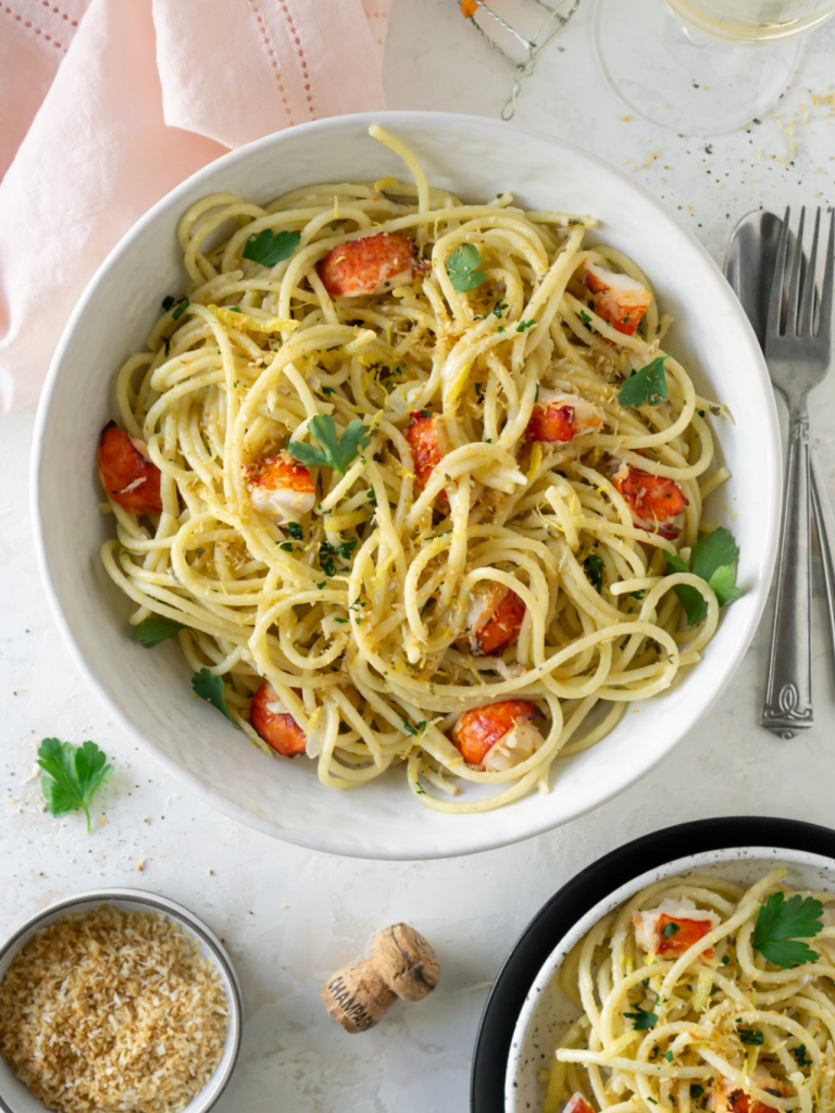 lobster pasta in a large white bowl with a pink napkin