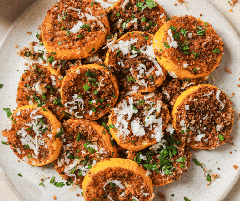 roasted yellow squash on a white plate topped with cheese and parsley