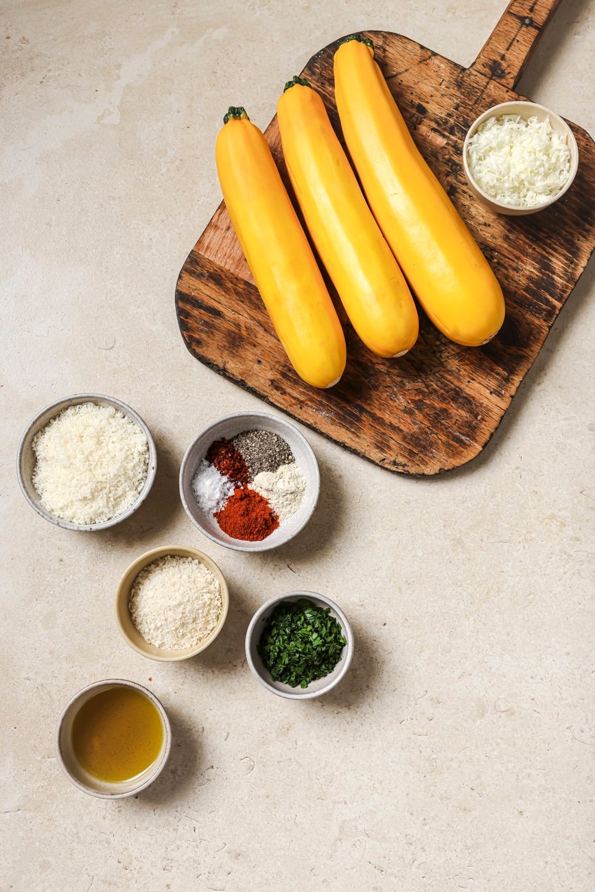 yellow squash, parmesan cheese, spices, parsley, and olive oil in small ingredient bowls.