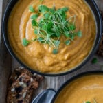 roasted butternut squash soup in a black bowl with micro greens