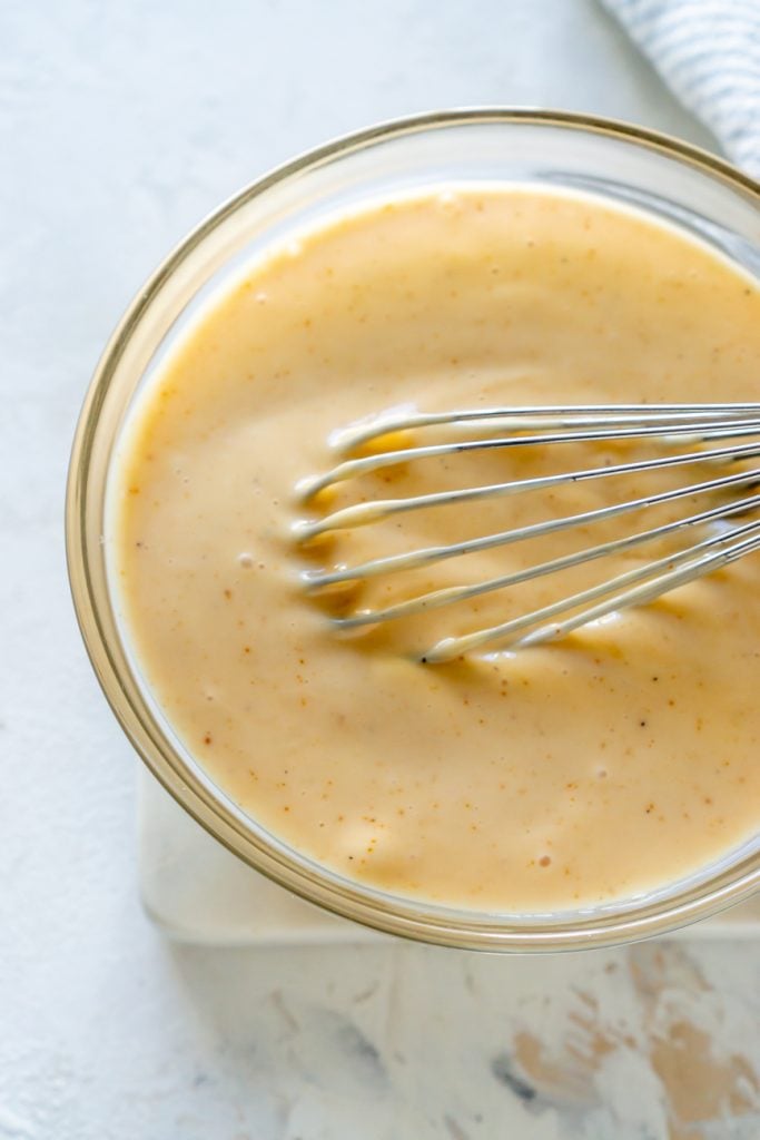 spicy mayo in a clear bowl with a whisk