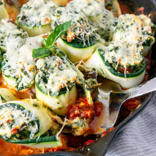 zucchini lasagna rolls in a skillet with a spatula