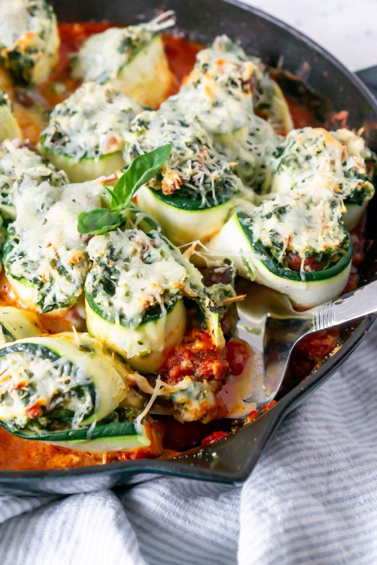 zucchini lasagna rolls in a skillet with a spatula