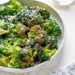 air fryer broccoli in a white bowl and lemon wedges