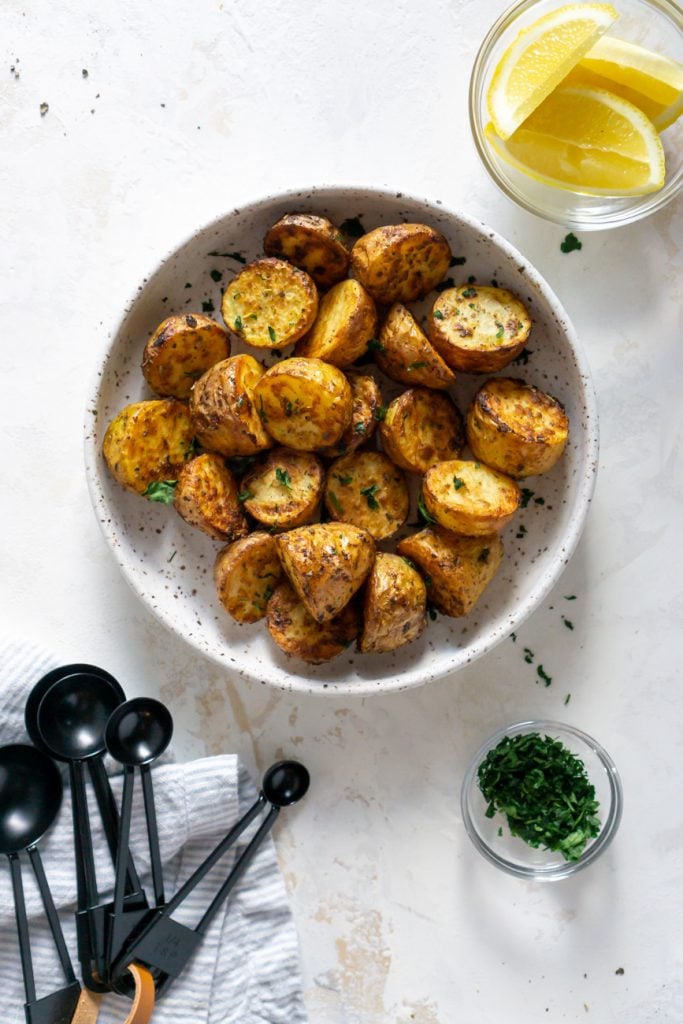 air fryer potatoes in a white bowl with black measuring spoons