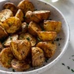air fryer potatoes in a white bowl with lemons