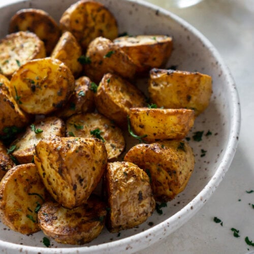 air fryer potatoes in a white bowl with lemons