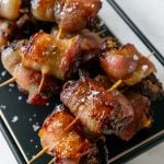 bacon wrapped dates with toothpicks on a black plate