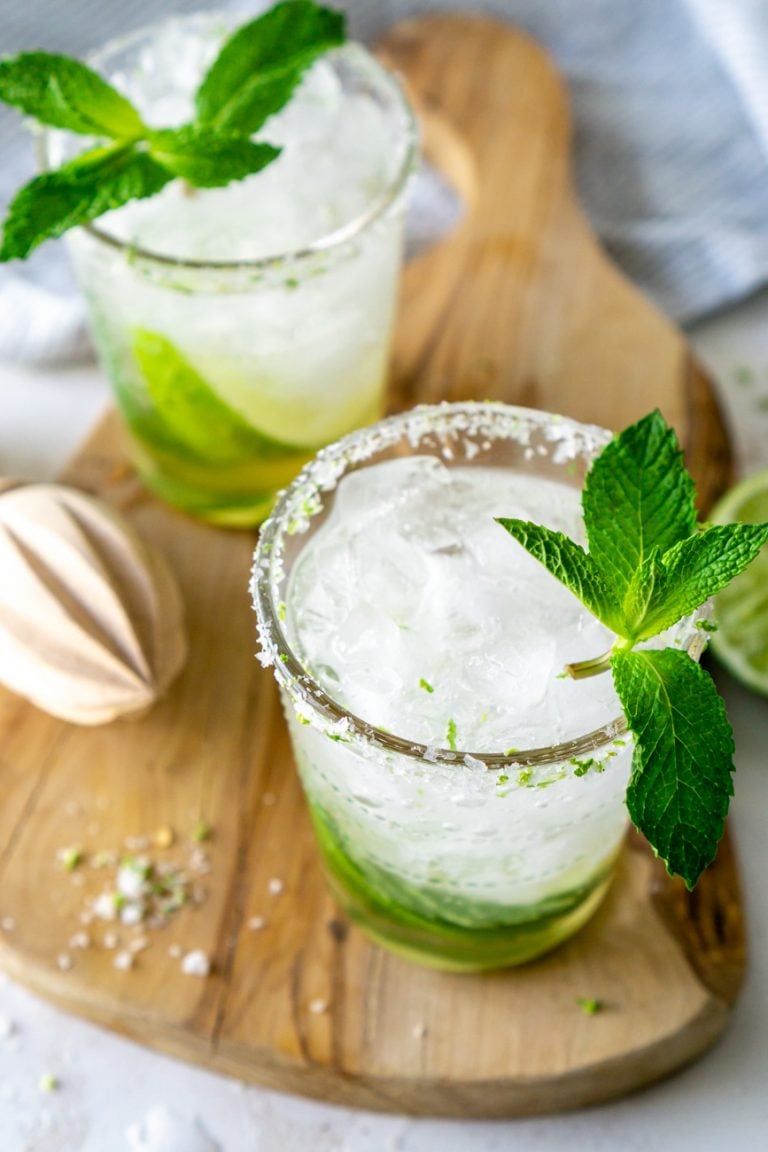 two mint mojitos on a wood serving tray