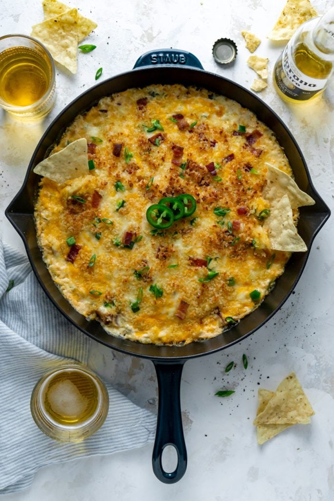 jalapeno popper dip in a skillet with chips and beer