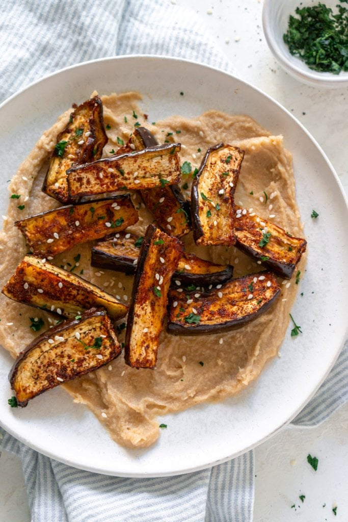 air fryer eggplant fries on a white plant with tahini sauce