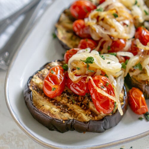 baked eggplant steaks on a plate with a fork