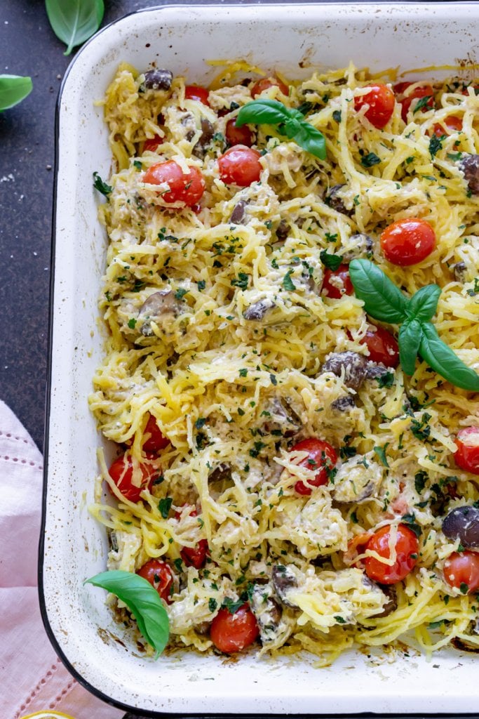 bakes spaghetti squash with tomatoes in a white pan