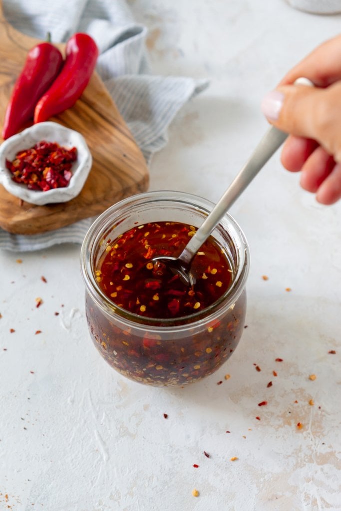 stirring sauce in a glass jar with a silver spoon