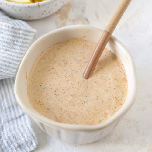 crab cake sauce in a white bowl with lemon wedges