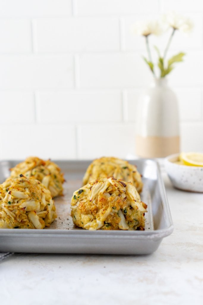 maryland crab cakes on a baking sheet with flowers in the background