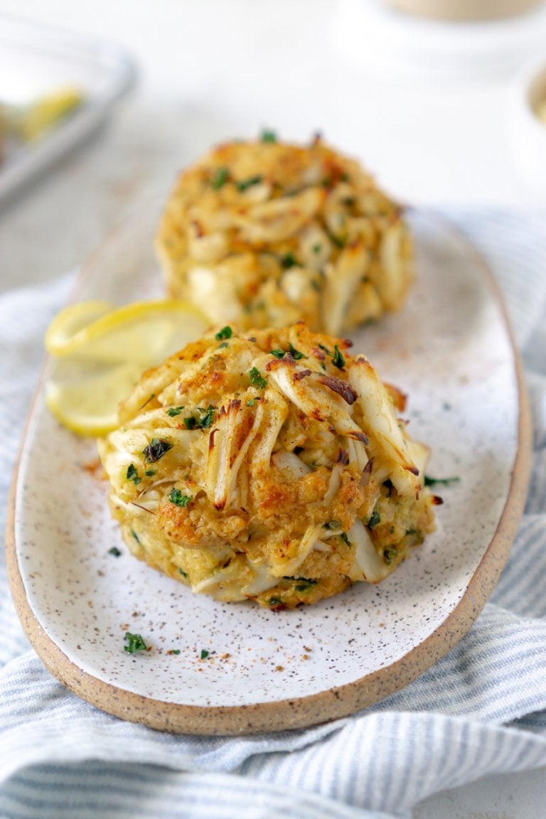 two crab cakes on a plate with lemon slice