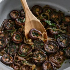 wooden spoon scooping mushrooms in a pan