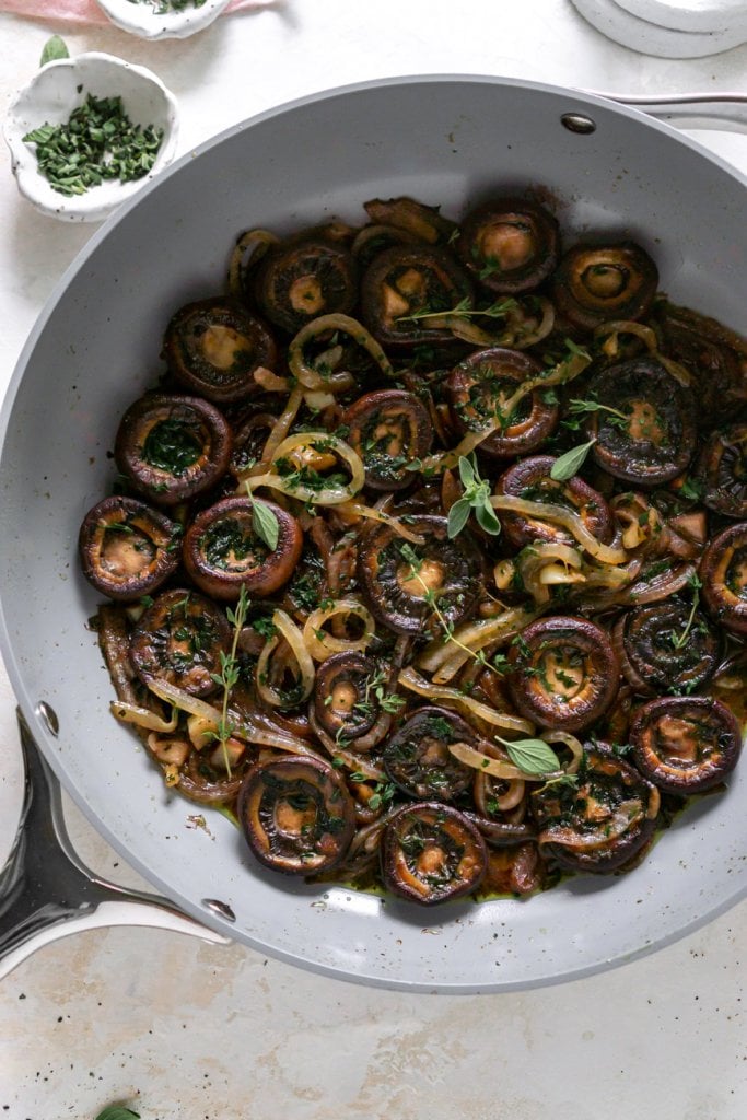 red wine mushrooms in a grey pan with fresh herbs