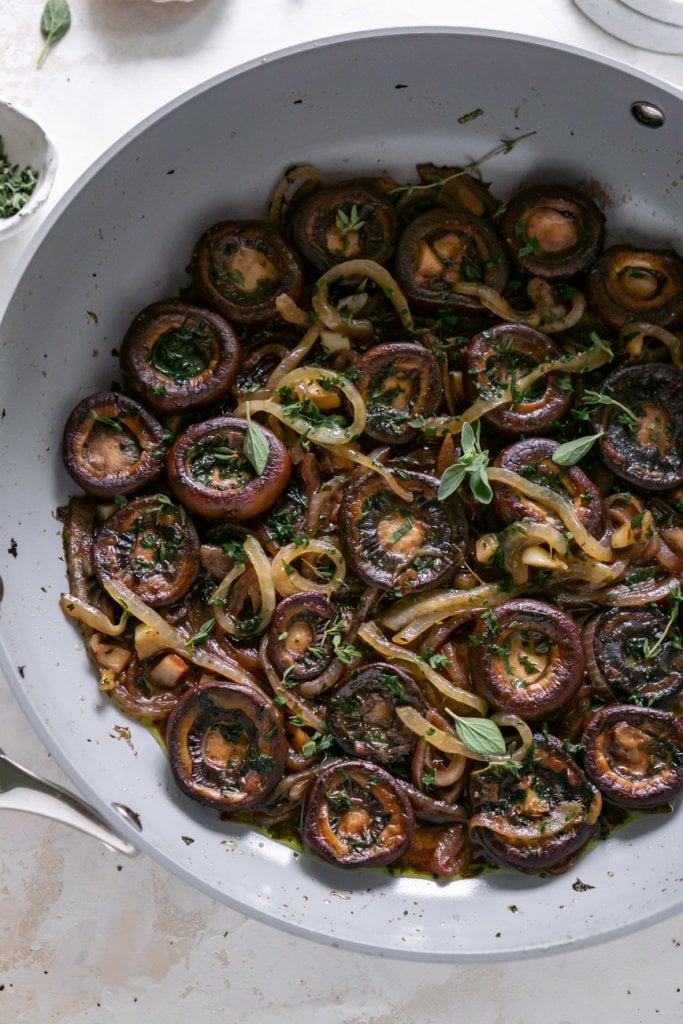 a grey pan with mushrooms and fresh herbs