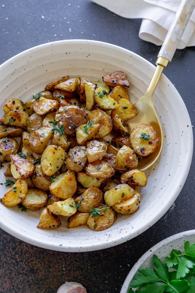 roasted garlic potatoes in a bowl with a gold spoon