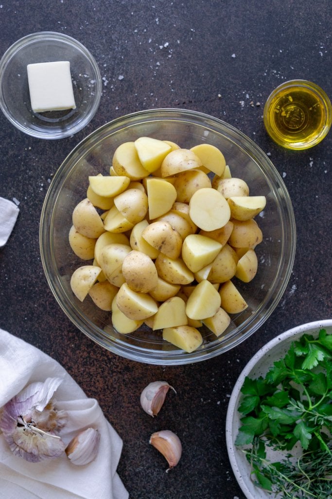 ingredients in small bowls: potatoes, parsley, garlic, butter, olive oil