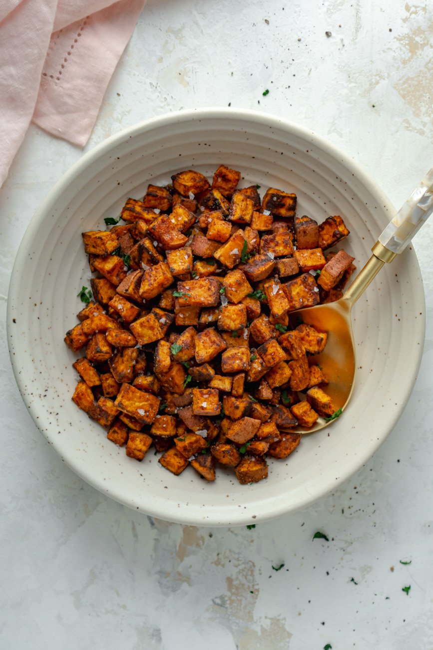 Roasted sweet potatoes in a bowl with a pink napkin.