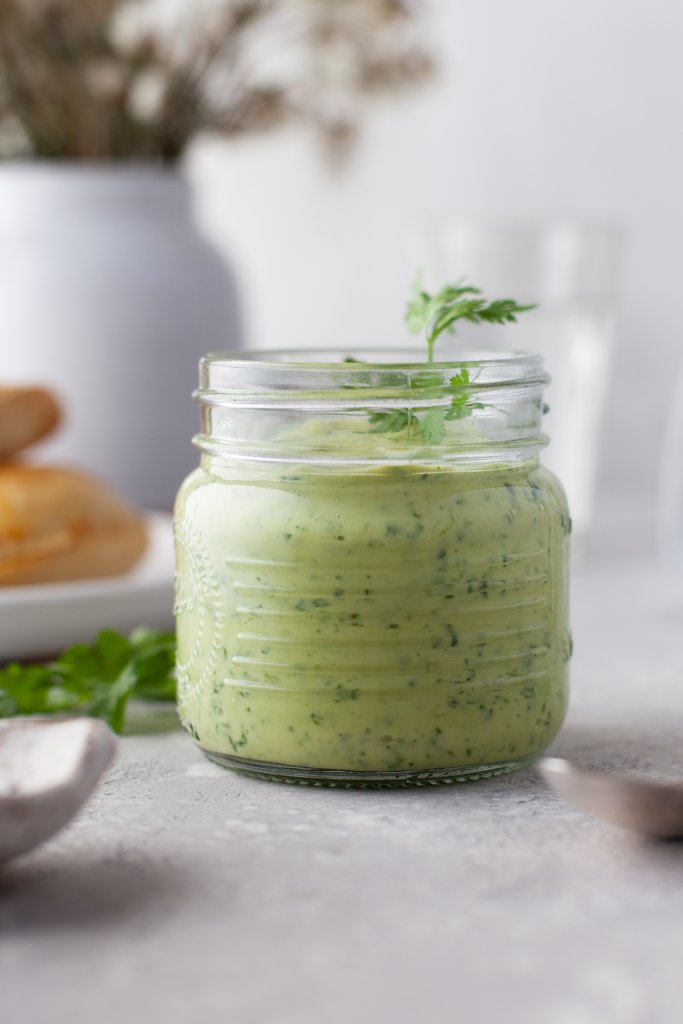 empanada sauce in a glass jar, flowers behind